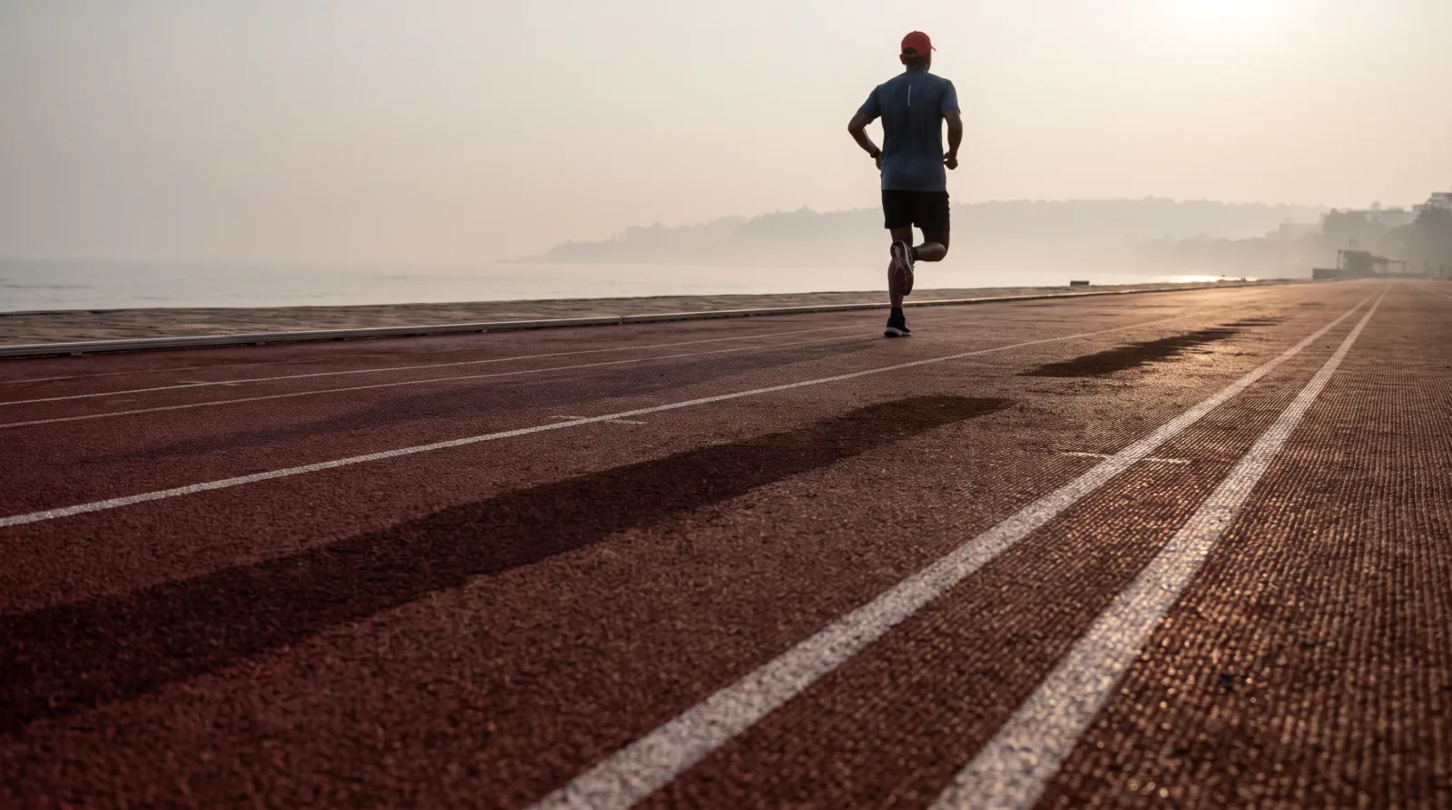 Lane lines on a running track, receding into low light.